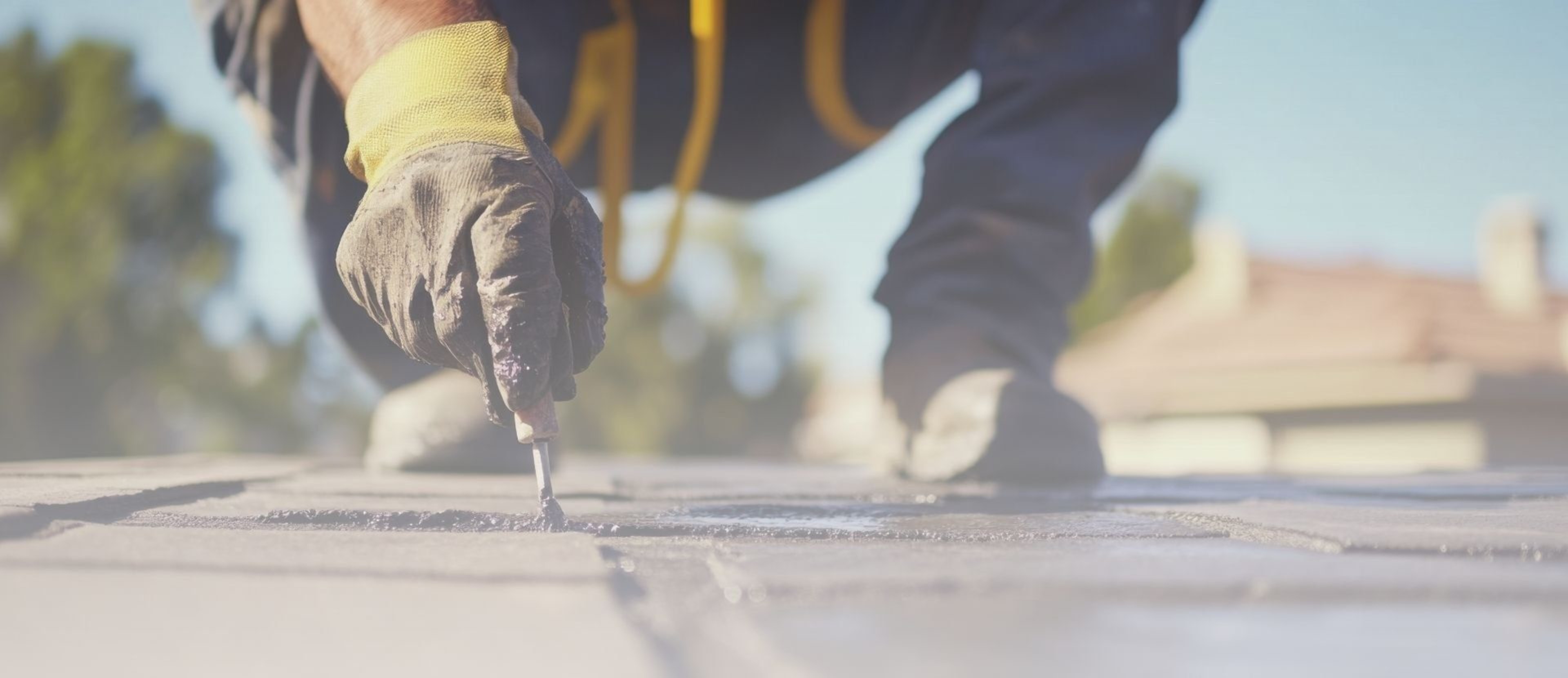 Gloved hand holding a tool on top of a roof.